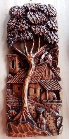 a ceramic wall hanging with a tree and house in the middle, on a table