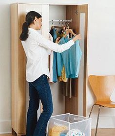 a woman standing in front of a closet with clothes