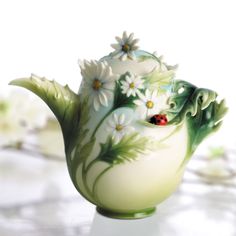 a ceramic teapot with daisies and ladybugs painted on it