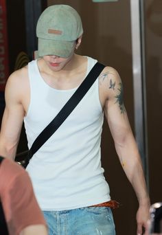 a man wearing a hat and carrying a cell phone in his hand while walking through an airport