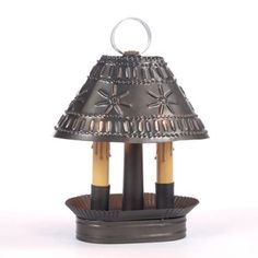 a lamp that is sitting on top of a stand with two candles in the middle