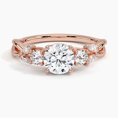 a rose gold engagement ring with three stones on the band and an oval center stone