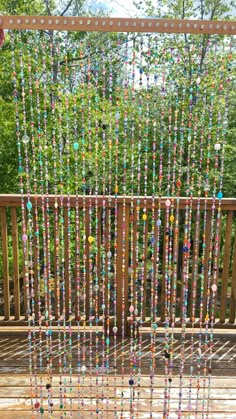 a wooden deck with beads hanging from it's sides and trees in the background