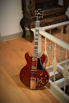 an electric guitar sitting on the ground in front of a stair case and railings