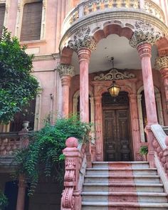 an ornate building with stairs and plants on the outside, next to it is a light fixture