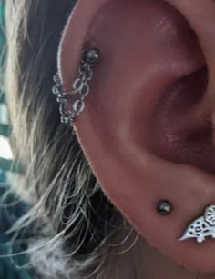 an ear piercing is shown with chains attached to the side and a bird on it