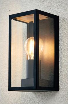 a light that is on the wall next to a white stucco wall with a black frame