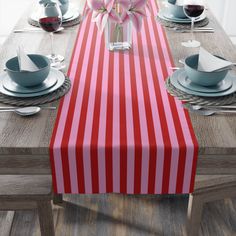 the table is set with red and white striped linens, plates, silverware, and pink flowers