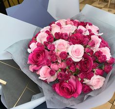 a bouquet of pink and red roses sitting on top of a table