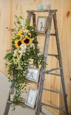 a ladder decorated with sunflowers and greenery next to a wooden paneled wall