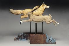 a sculpture of two running deers on top of each other in front of a gray background