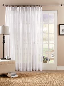 a living room with a couch, chair and window covered in white sheer curtaines