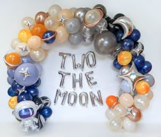 a wreath made out of balloons with the words two the moon written in silver and orange