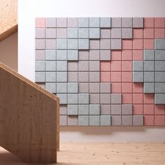 a wooden stair case next to a pink and gray wall