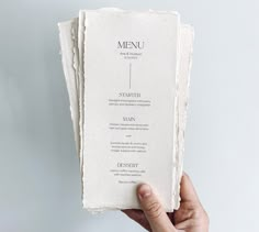 a person holding up a menu in their left hand, with the rest of the menu on it