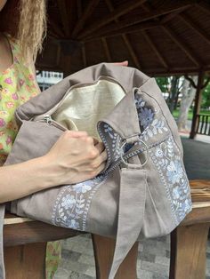 a woman is sitting on a bench with a purse in her hand and holding it