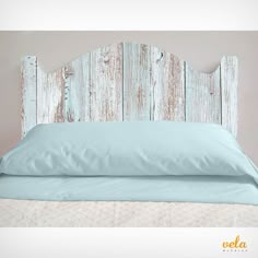 a white headboard made out of wood with light blue sheets and pillows on it