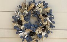 a wreath is hanging on the side of a door with dried flowers and leaves around it