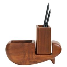 a wooden pen holder with two pens and pencils sticking out of it's sides