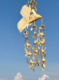 a wind chime hanging from the side of a blue sky with clouds in the background