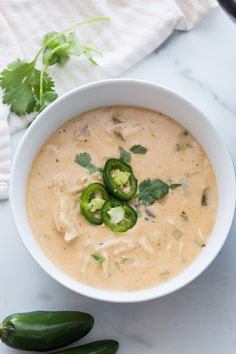 a white bowl filled with soup next to two green peppers