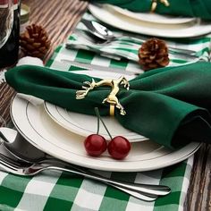 the place setting is set with two cherries on the plate and green napkins