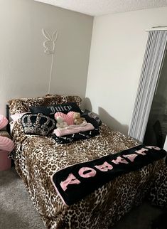 a leopard print bed spread with pink and black accessories on it in a girls'bedroom