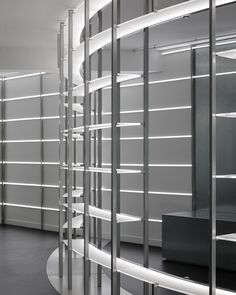 the interior of a modern building with glass walls and metal shelves on either side of the room