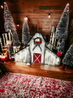 a barn decorated for christmas with trees and candles in the foreground, on a red rug