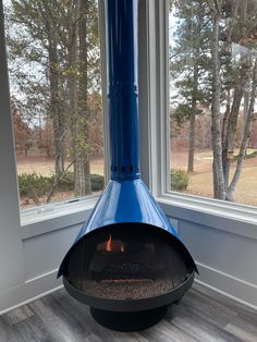 a blue fire place sitting in front of a large window next to a wooden floor