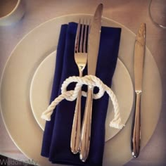 a white plate topped with silverware next to a blue napkin and fork set on top of it