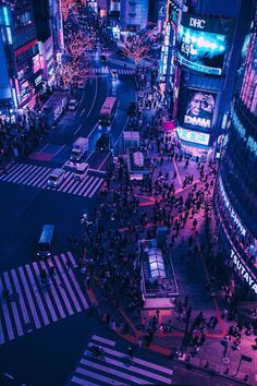 an aerial view of a busy city street at night with people crossing the street and cars driving on the road