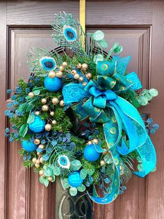 a wreath with blue and green decorations hanging on a door