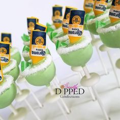 there are many green desserts on sticks with white frosting and toppings in them