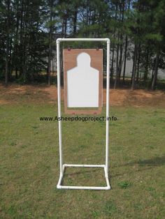 a sign in the middle of a grassy area with trees behind it and a white coat hanger