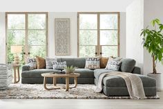 a living room filled with lots of furniture next to two large windows and a rug on the floor