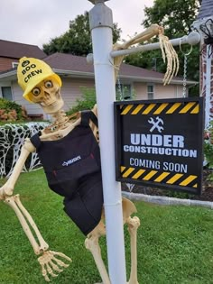 a skeleton dressed as a construction worker leaning against a pole