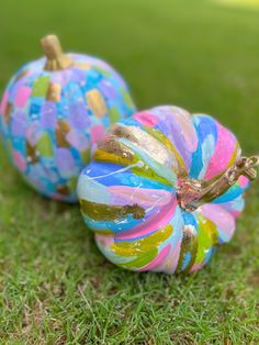 two painted pumpkins sitting in the grass