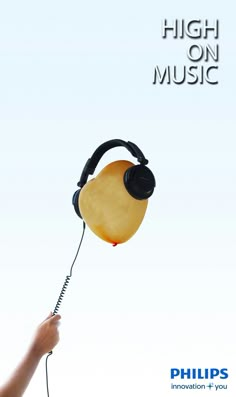 a hand holding a yellow object with headphones attached to it's ear and the words high on music above it