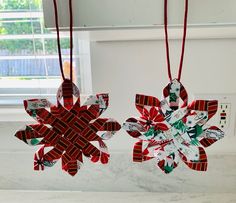 two red and green ornaments hanging from a window sill