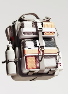 the back side of a white backpack with multiple compartments and straps on it, hanging in the air