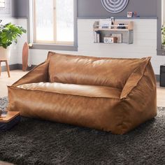 a large brown leather couch sitting on top of a carpeted floor next to a window