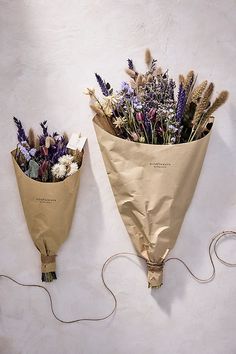 two bouquets wrapped in brown paper are sitting on the wall next to each other