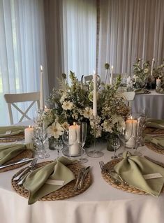 the table is set with silverware, candles and flowers in vases on it