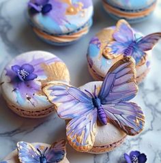 there are some cookies decorated with butterflies on top of each cookie, and one has purple icing