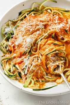 a white bowl filled with pasta covered in sauce and topped with parmesan cheese