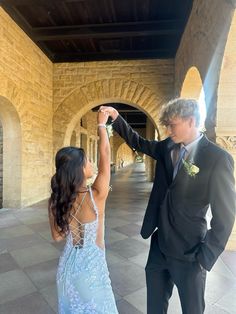 a man and woman in formal wear standing next to each other with their arms raised