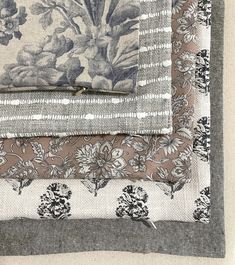 four pieces of fabric with flowers and leaves on them, all in different shades of grey