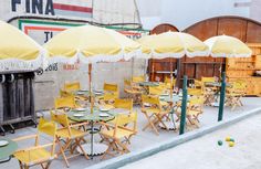 tables and chairs with yellow umbrellas outside