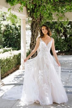 a woman in a wedding dress standing under a tree